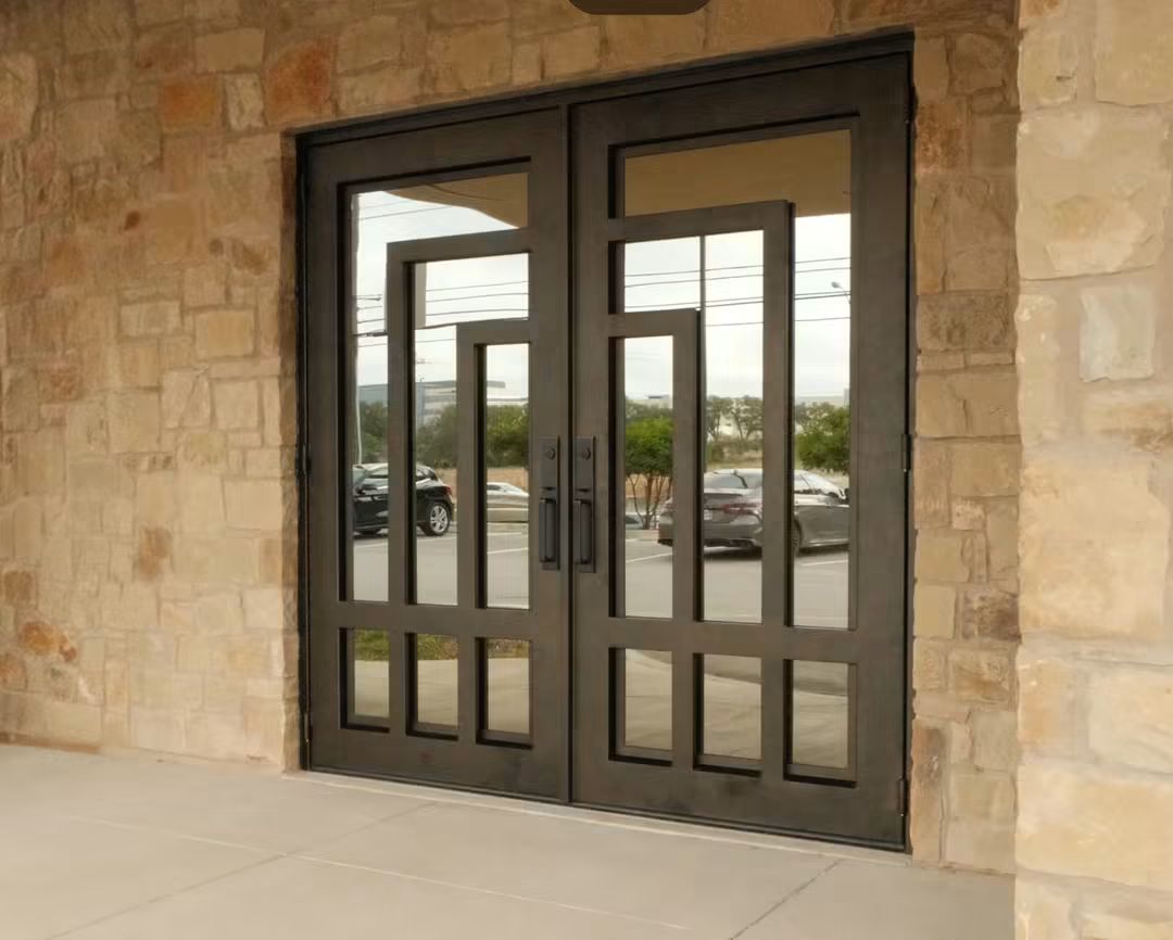 Black steel double doors with large glass panels set in a stone wall